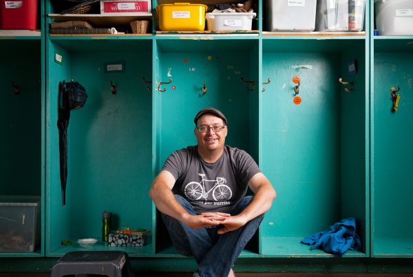 Stefan Lynch Strassfeld sits in a cubby hole in a classroom at Alpha Alternative School