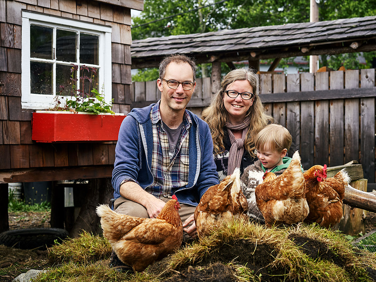 Artists Tyler Brett and Kerri Reid, co-directors of the Sointula Art Shed, with their son Teddy and their chickens, all named Darlene, in front of the chicken coop Tyler built with help from Teddy. Tyler also works as a paramedic, and was recently hired as Sointula's first Community Paramedic, and Kerri works from home for Living Oceans Society. Sointula, British Columbia.