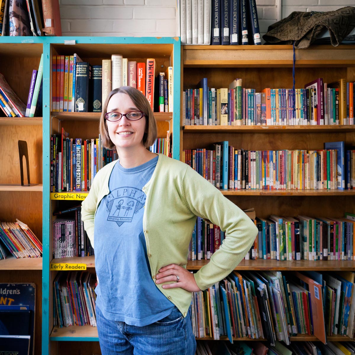 Maggie Marelli stands in front of book shelves at Alpha Alternative School