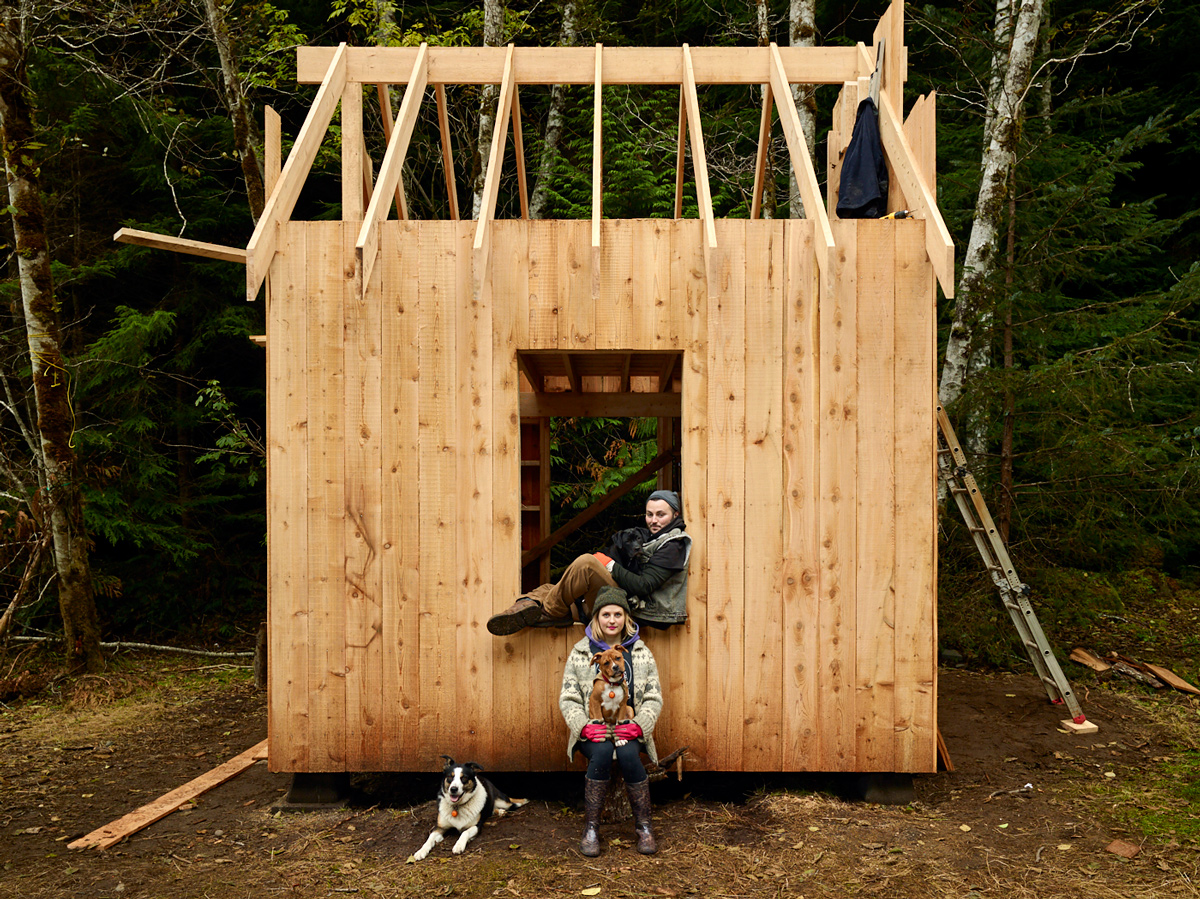 andi grace rose and logan hope rose with their dogs dolly, bousha, and clover. Photographed with the first timber frame structure at their new home, fiddlehead farm on Malcolm Island. Sointula, British Columbia.
